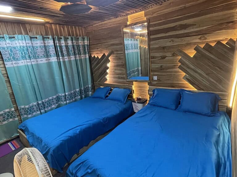 Cozy wooden cabin bedroom with blue bedding and unique wall design, perfect for romantic getaways.