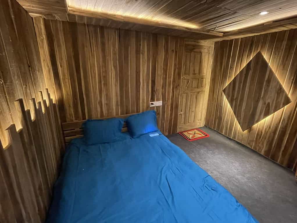 Cozy wooden cabin bedroom with blue bedding and warm soft lighting for relaxation.