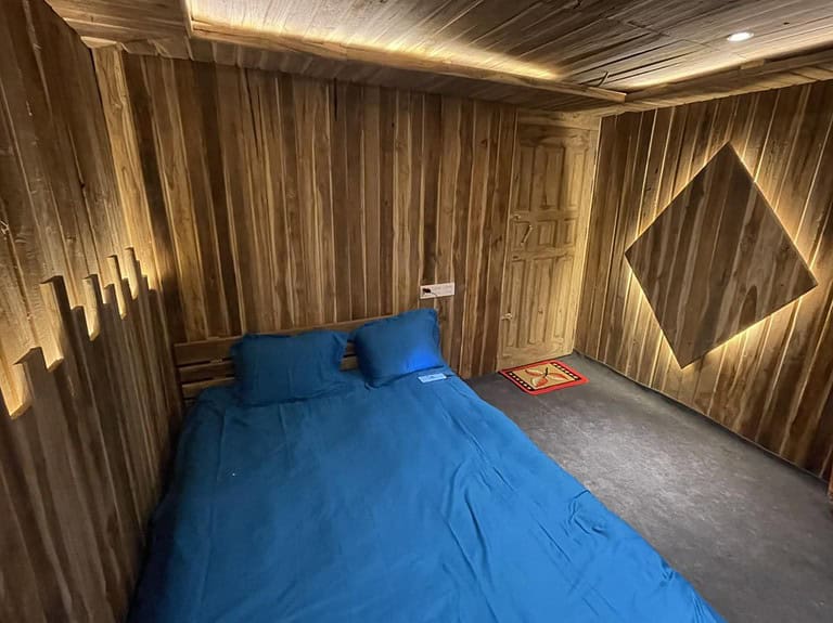 Cozy wooden cabin bedroom with blue bedding and warm soft lighting for relaxation.